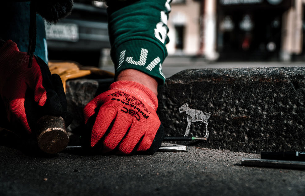 Carving petroglyphs on the sidewalk edging
