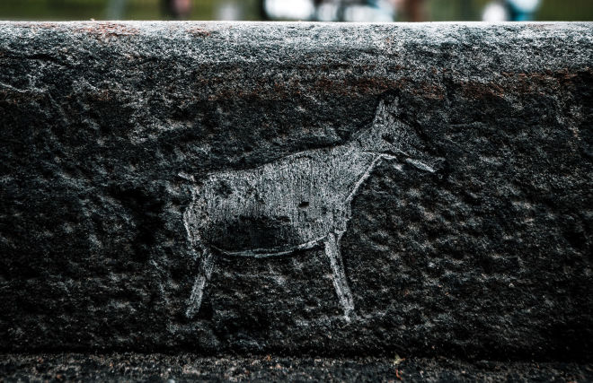 Carving petroglyphs on the sidewalk edging