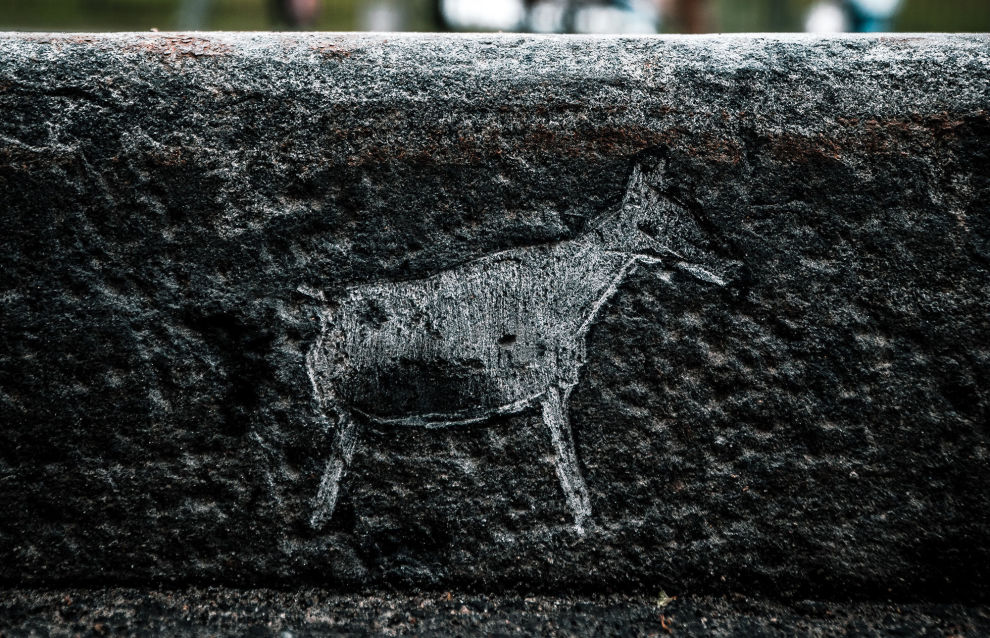 Carving petroglyphs on the sidewalk edging