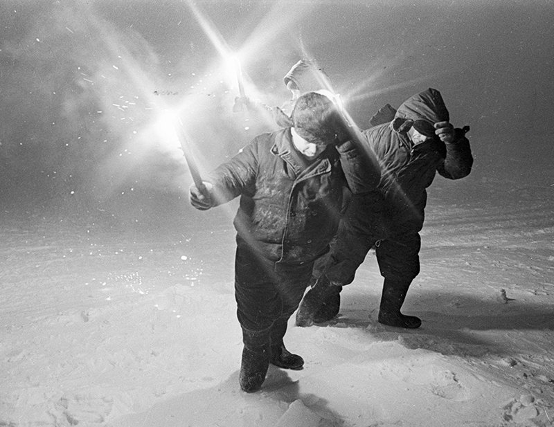 Explorers with lamps in a snowstorm