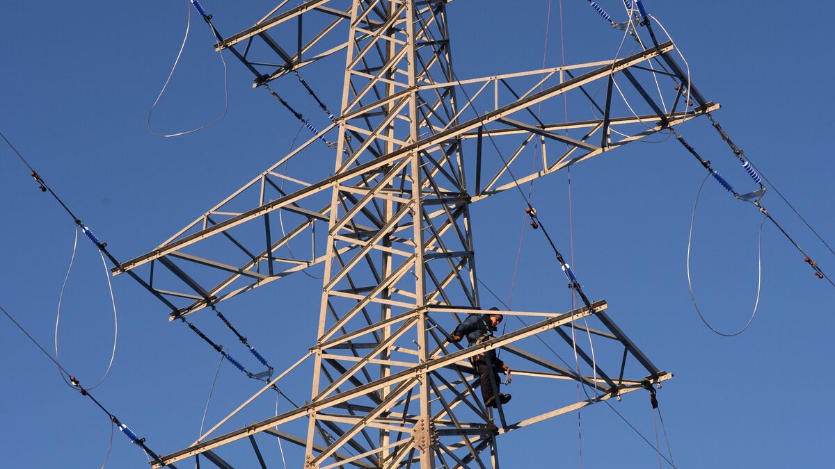 A worker assembles a high-voltage power transmission line 