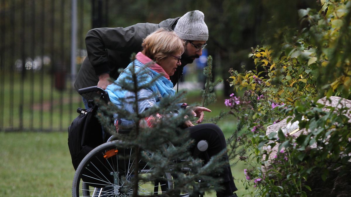 Woman in a wheelchair with an attendant in a park