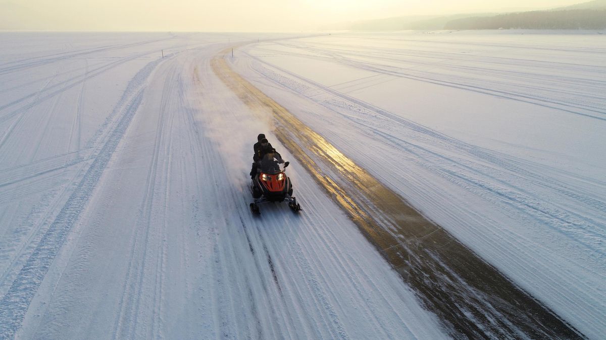 A snowmobile travels along an ice road